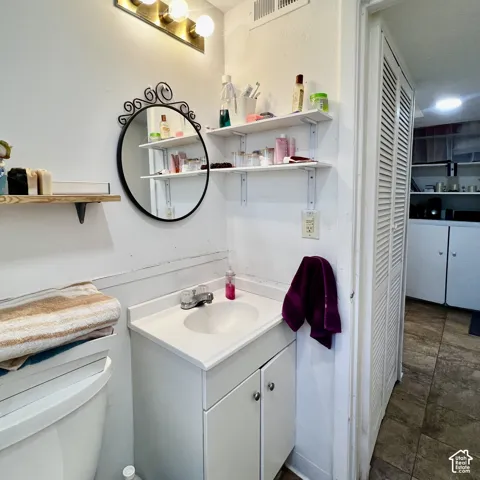 Vanity with integrated sink, wall-mounted shelving, and overhead lighting