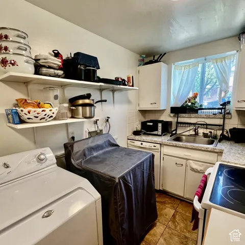 Kitchen with a double basin sink, white cabinetry, and tiled flooring