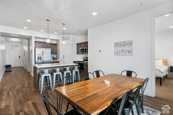 Kitchen featuring wood-finish flooring, a central island with a solid-surface countertop, stainless steel appliances, and dual pendant lighting