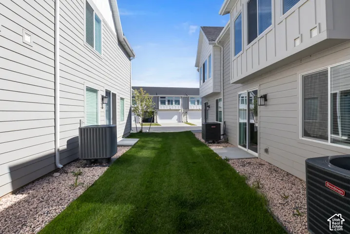 Exterior featuring horizontal lap siding, vertical board-and-batten accents, sliding glass doors, and a grass lawn with decorative stone borders