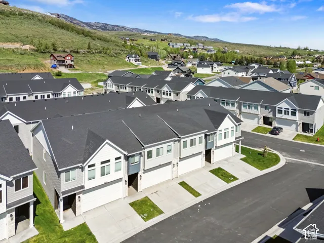 Multi-level townhome exterior featuring shingled roofing, lap siding, attached two-car garages, concrete driveways, and mountain scenery