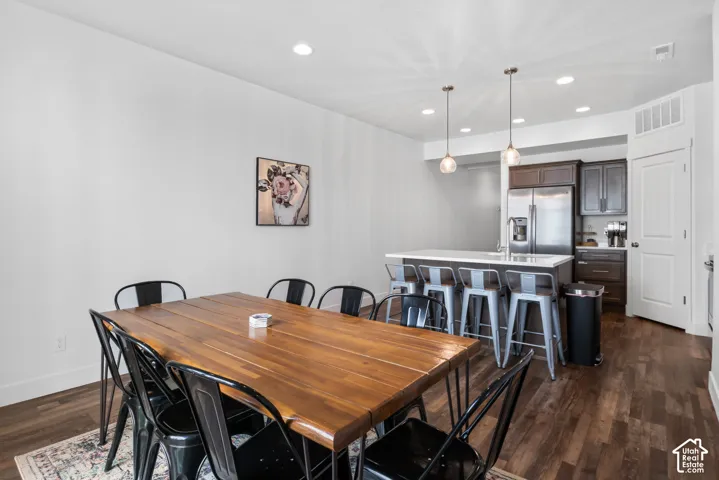 Kitchen featuring a central island with a stone countertop, wood-finish cabinetry, stainless steel appliances, recessed ceiling lighting, and wood-finish flooring