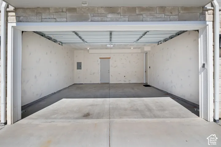 Two-car garage featuring a concrete floor, finished interior walls, and stone veneer exterior detailing