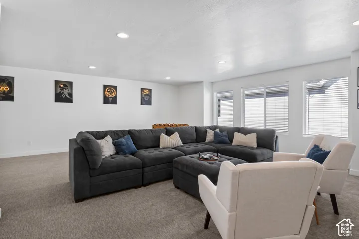 Neutral-toned wall-to-wall carpeting, recessed ceiling lighting, and multiple windows with horizontal blinds