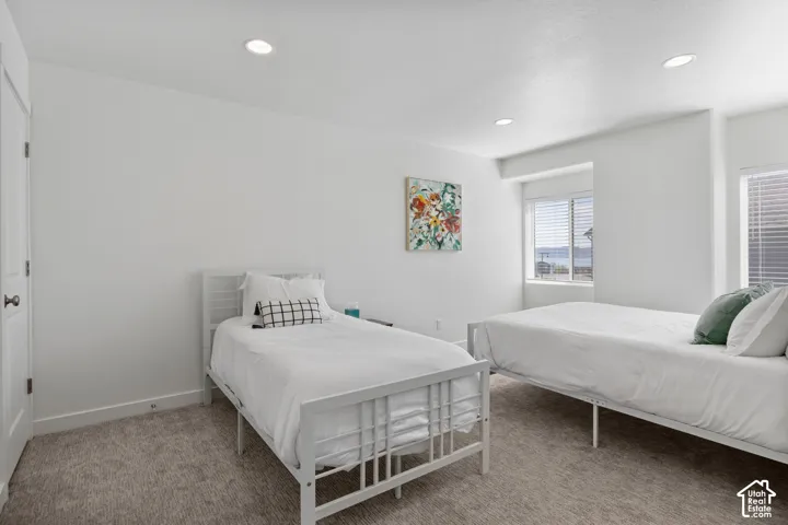 Neutral-toned carpeting, recessed ceiling lighting, and dual windows with horizontal blinds
