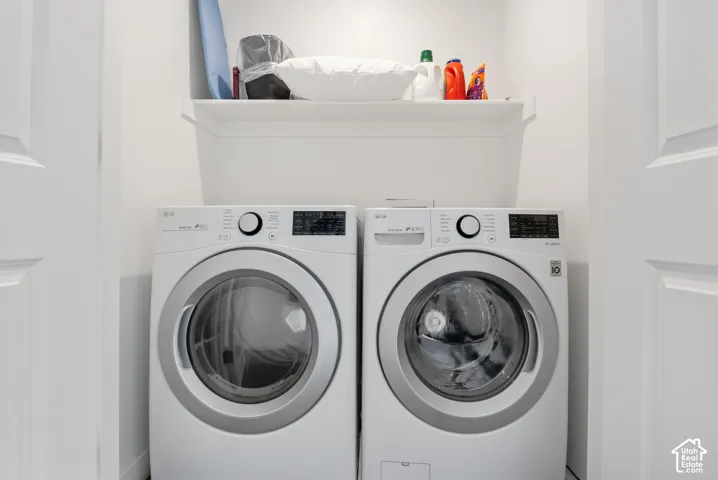 Dedicated laundry area featuring a white built-in storage shelf and side-by-side white high-efficiency front-load appliances