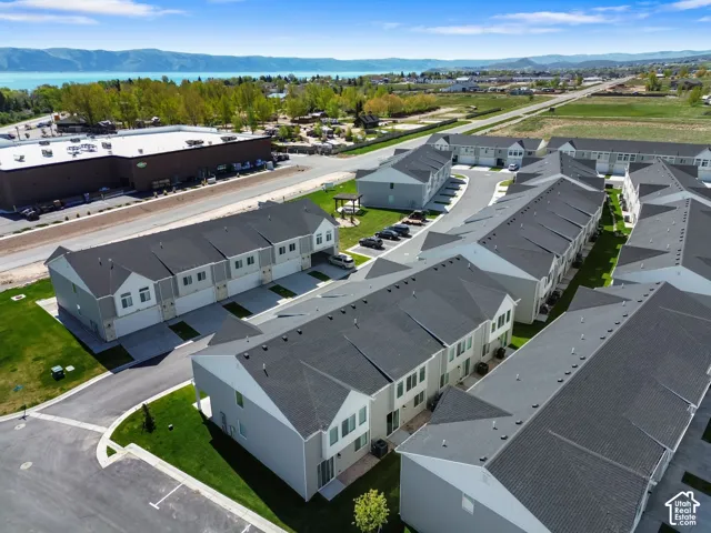 Aerial perspective of a multi-unit residential complex featuring asphalt shingle roofing, attached garage parking, concrete driveways, and manicured landscaping