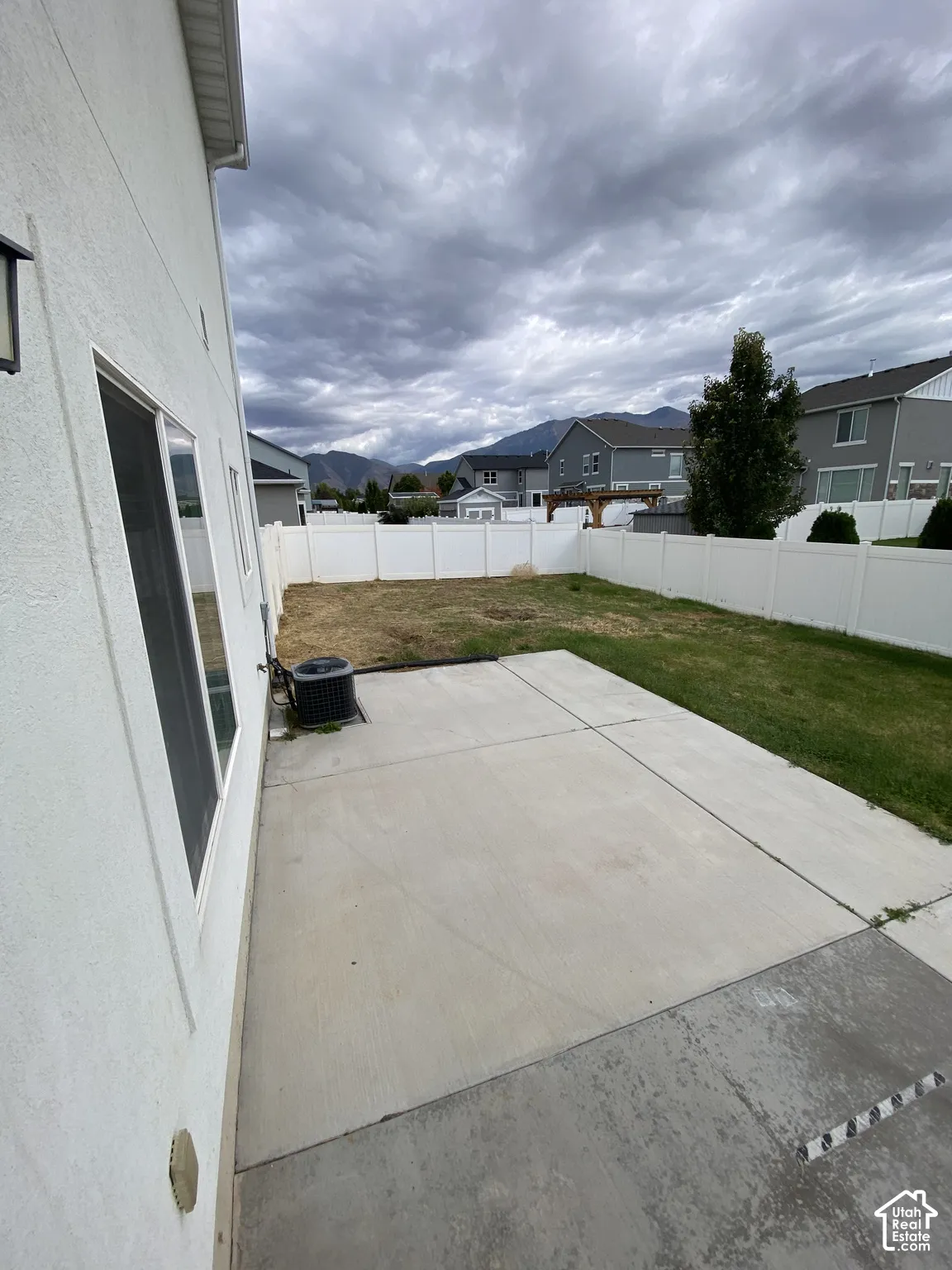Concrete patio, fenced backyard, and mountain backdrop