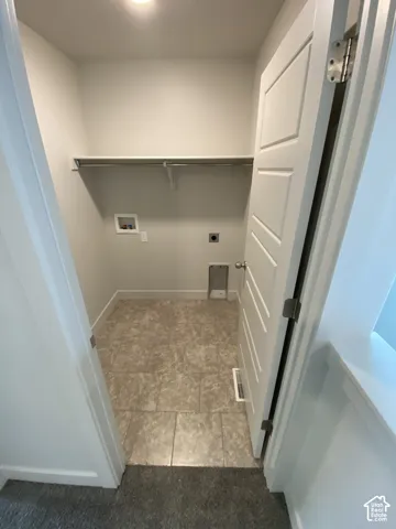 Dedicated utility area featuring tile flooring, a wall-mounted shelving unit with a metal hanging rod, and a five-panel interior door