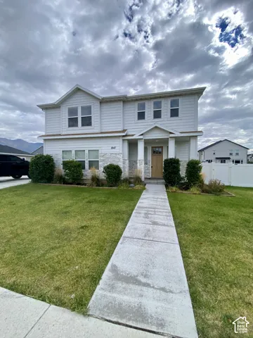 Two-story exterior featuring white horizontal siding, stone veneer accents, a covered front porch with columns, and a concrete walkway