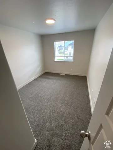 Neutral-toned interior featuring wall-to-wall carpeting, a recessed ceiling light, and a single-pane window with white trim