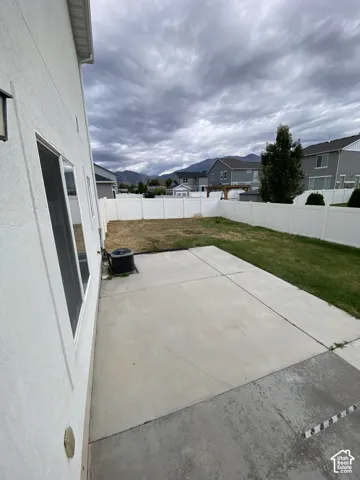 Concrete patio, fenced backyard, and mountain backdrop