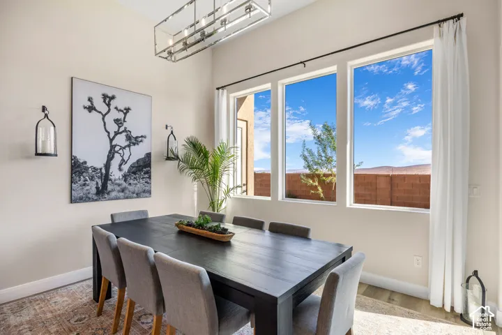 High ceilings featuring a rectangular metallic chandelier, large windows with mountain scenery, and matte black wall-mounted sconces