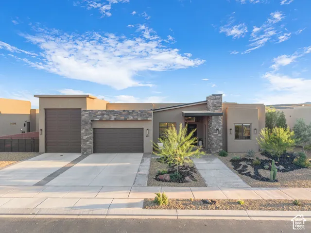 Contemporary exterior featuring stucco siding, stone veneer accents, multi-car garage, and xeriscaped front yard