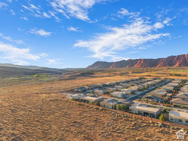 Aerial perspective featuring arid desert terrain, expansive mountain topography, and a residential subdivision