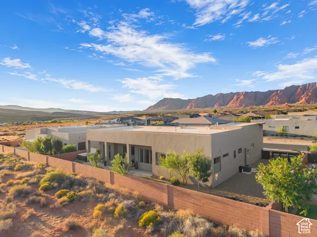 Stucco exterior residence featuring a covered patio, fenced perimeter, and mountain backdrop