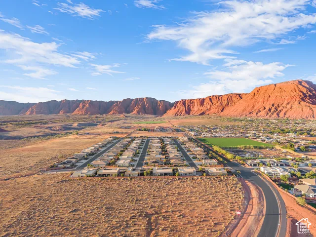 Aerial perspective of a planned residential community featuring paved roadways and natural desert landscape backdropped by prominent red rock mountain formations