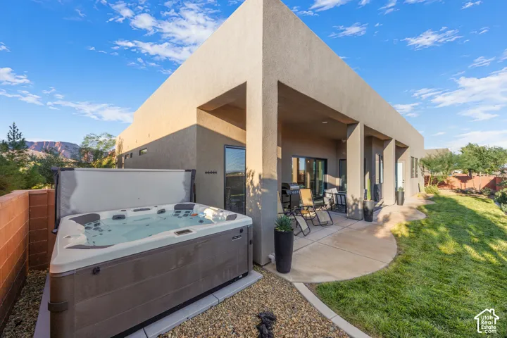 Covered concrete patio with stucco pillars, integrated spa, and desert mountain backdrop