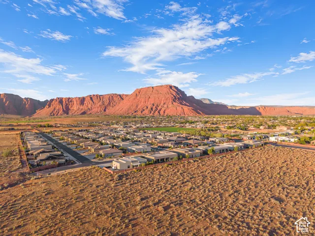 Aerial perspective of residential community featuring arid landscape surroundings and prominent red rock mountain backdrop