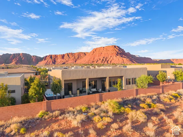 Stucco exterior residence featuring a covered patio, built-in hot tub, and masonry perimeter wall, set against a backdrop of prominent red rock formations
