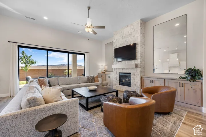High-ceiling living space featuring a stacked-stone fireplace with an integrated mantel, sliding glass doors, wood-finish flooring, and custom built-in cabinetry