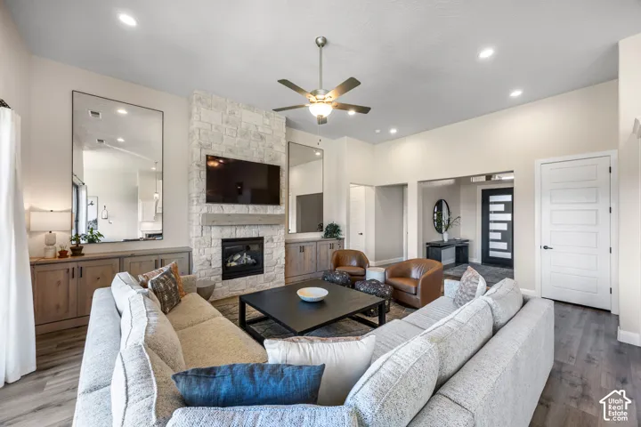Living area featuring a floor-to-ceiling stone fireplace, wood-finish flooring, built-in cabinetry, recessed lighting, and a ceiling fan