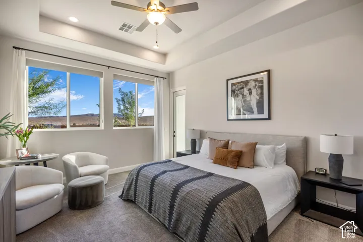 Tray ceiling, ceiling fan with integrated lighting, dual windows with mountain backdrop, and carpeted flooring