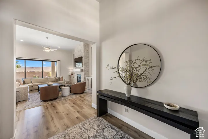 Entryway featuring high ceilings, wood-finish flooring, and a stone-clad fireplace surround with a built-in mantle