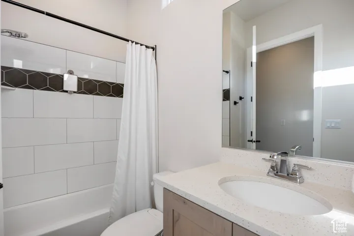Bathroom featuring a vanity with light-speckled stone-composite countertop, an integrated oval sink, and a shower-tub combination with horizontal wall tile and a decorative hexagonal accent inlay