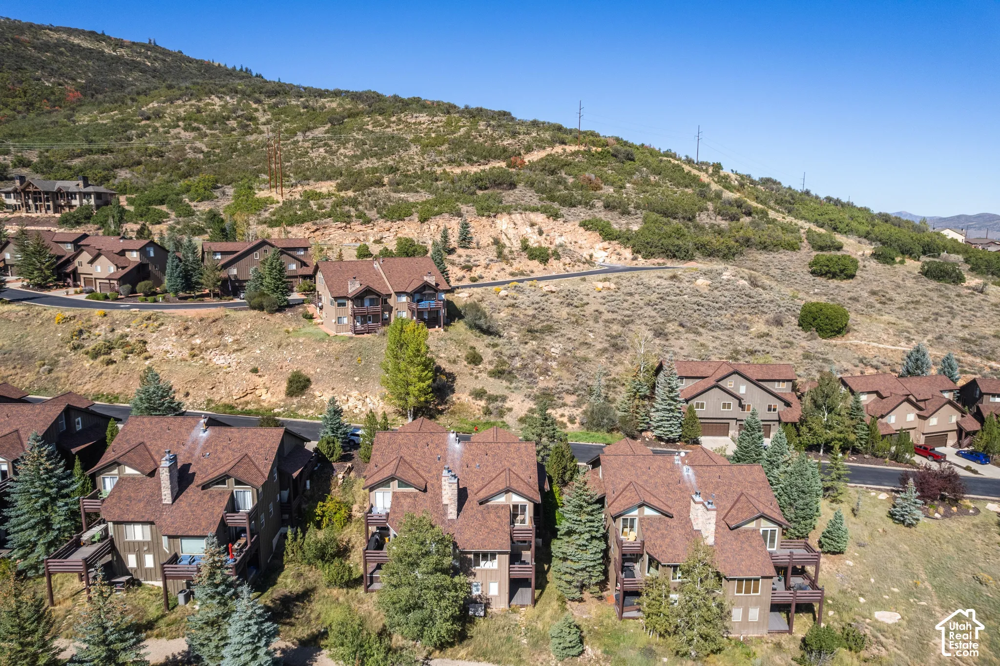 Property situated on a sloped terrain with multiple residences, offering a mountain backdrop and visible roadways