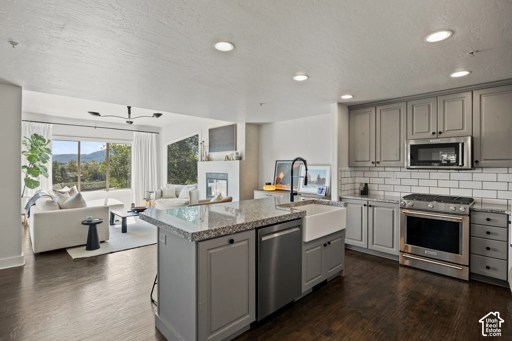Kitchen with shaker-style cabinetry, granite island countertop, and a farmhouse sink