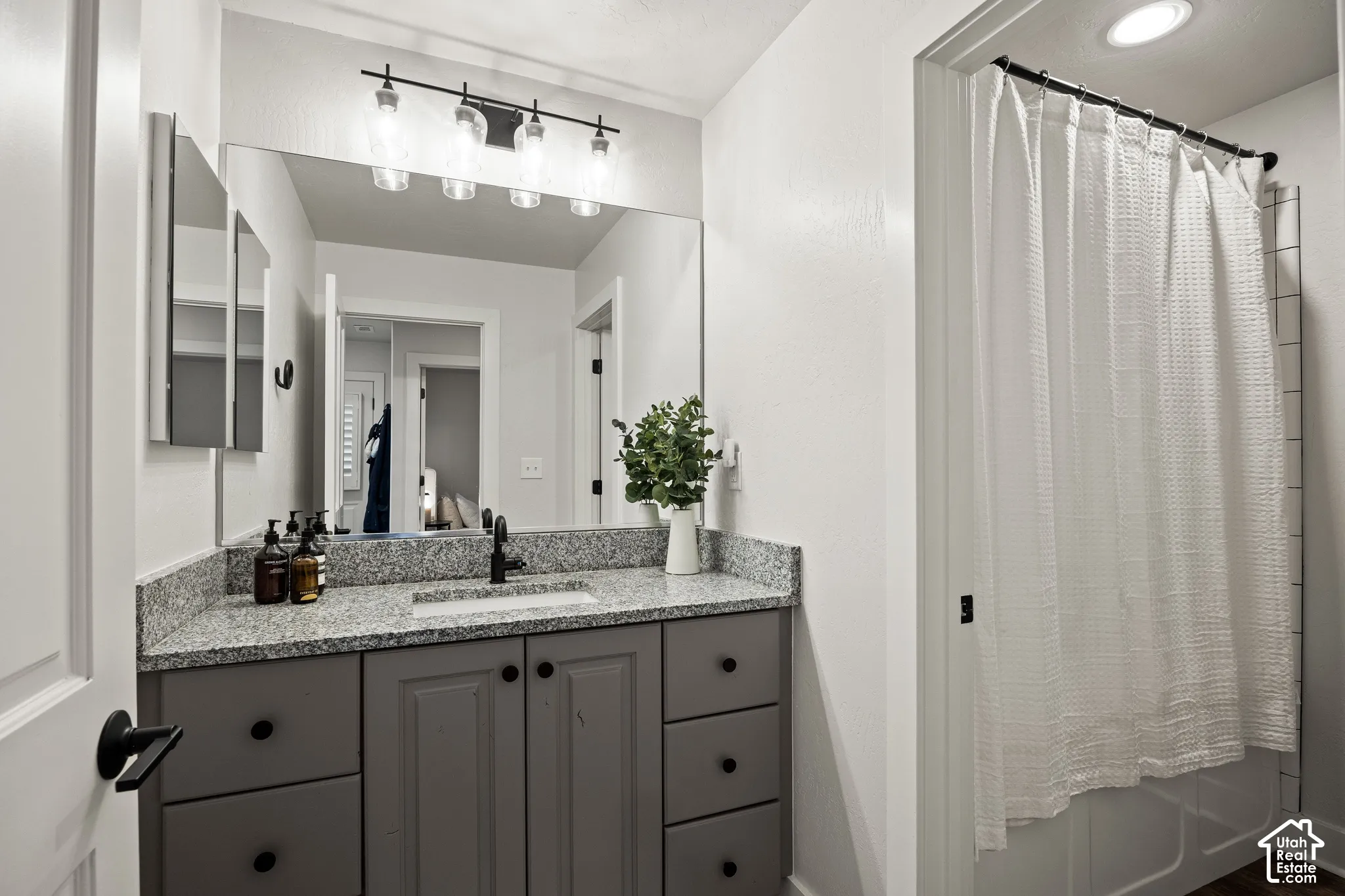Granite-finish countertop with an undermount sink, gray vanity cabinetry, and black hardware