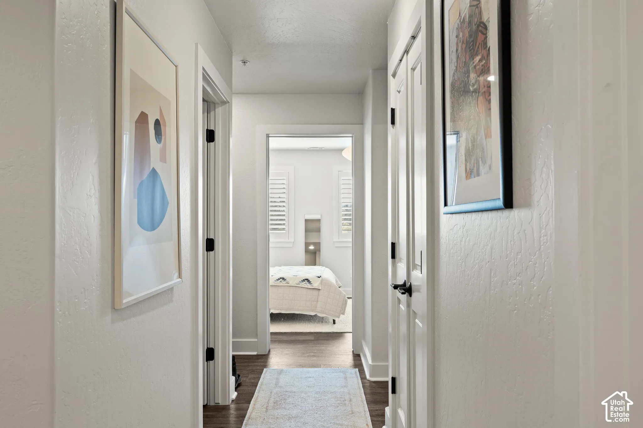 Hallway with dark wood-finish flooring, white walls, and bright overhead lighting