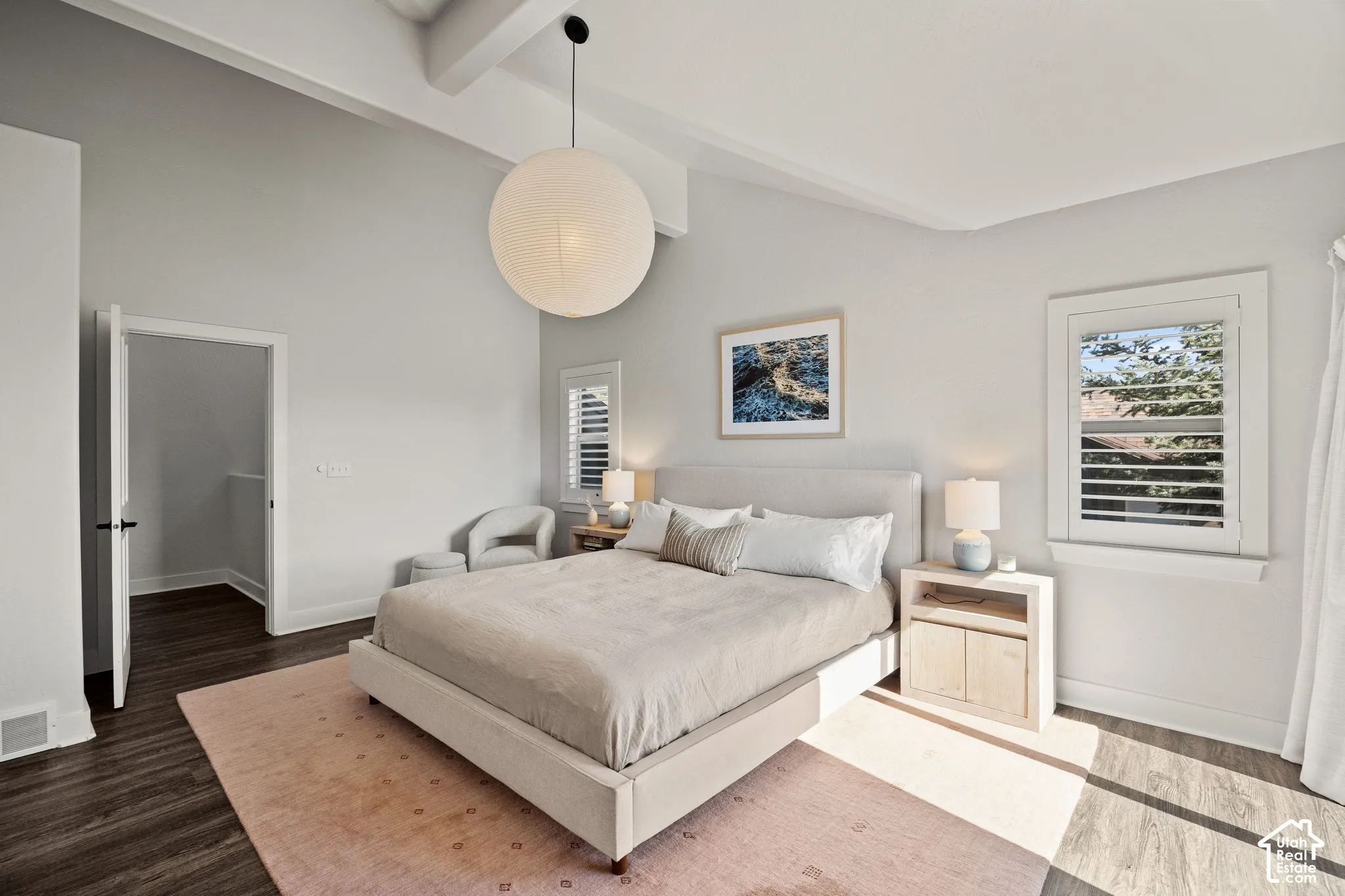 Vaulted ceilings with exposed beams, wood-finish flooring, white plantation shutters, and a white spherical pendant light fixture