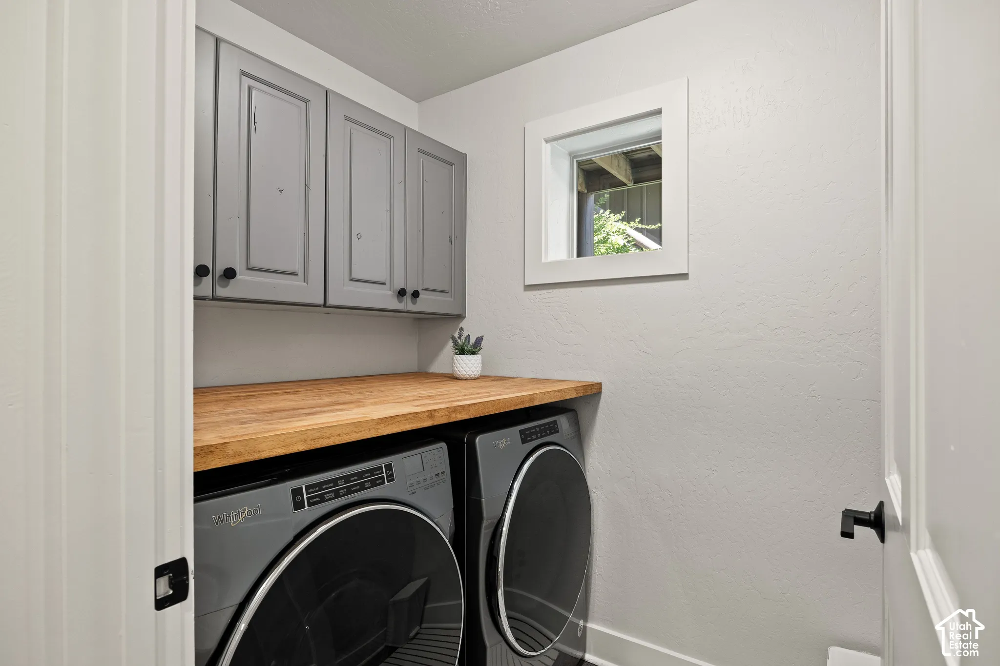 Laundry area featuring upper cabinetry, a wood-finish countertop, and a window for natural light