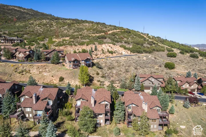 Property situated on a sloped terrain with multiple residences, offering a mountain backdrop and visible roadways