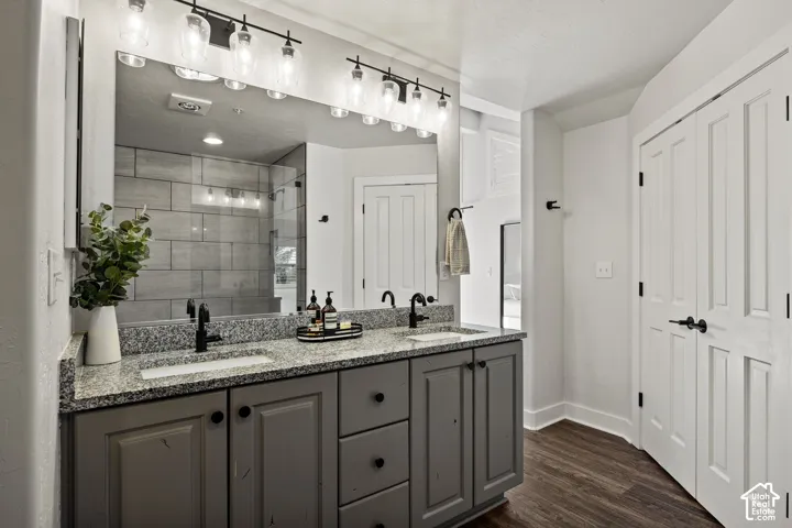 Dual vanity with granite countertop, matte black fixtures, and wood-finish flooring