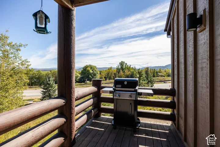 Outdoor porch with wood plank flooring, log railings, and a wood-paneled exterior