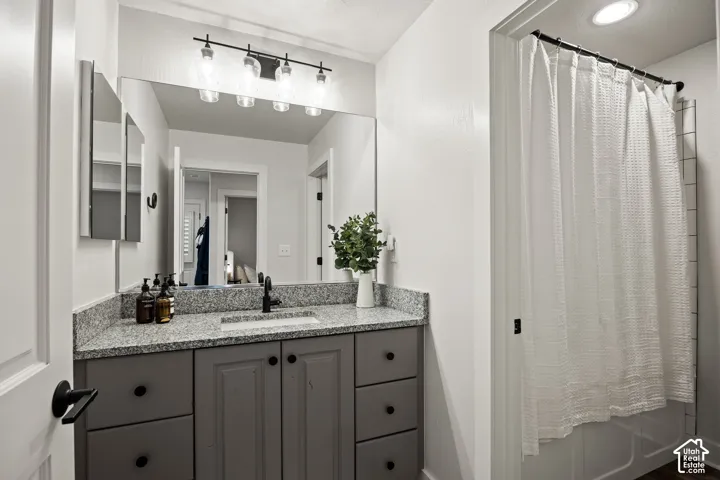 Granite-finish countertop with an undermount sink, gray vanity cabinetry, and black hardware