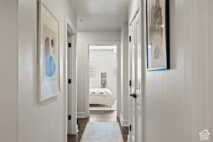 Hallway with dark wood-finish flooring, white walls, and bright overhead lighting