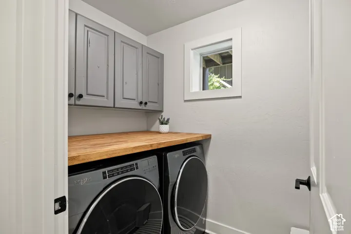 Laundry area featuring upper cabinetry, a wood-finish countertop, and a window for natural light