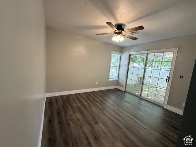 Room featuring wood-finish flooring, vaulted ceiling, sliding glass doors, and a ceiling fan with integrated lighting