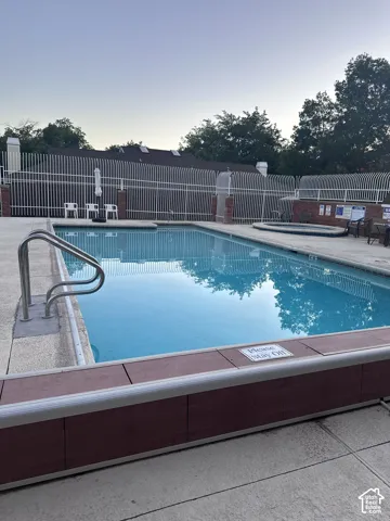 Swimming pool featuring a concrete deck, built-in spa, and metal perimeter fencing