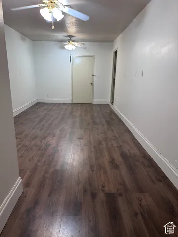 Interior space featuring wood-finish flooring, white walls, and dual ceiling fans with integrated lighting