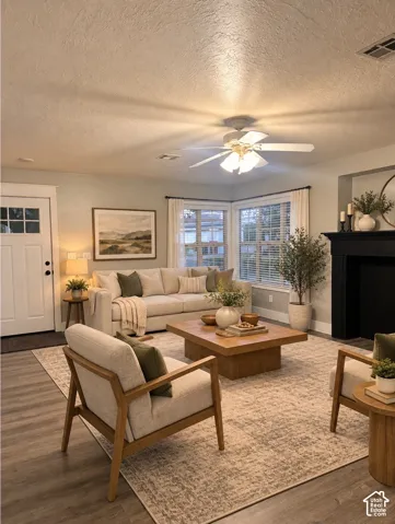 Virtually Staged. Living area featuring wood-finish flooring, a matte black fireplace surround, corner windows with natural lighting, a multi-light ceiling fan, and a paneled entry door with glass inserts