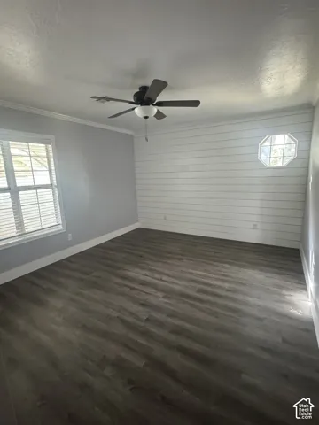 Primary Bedroom Interior room featuring wood-finish flooring, horizontal shiplap wall accent, an octagonal window, and a central ceiling fan with integrated lighting