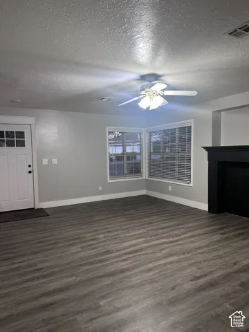 Living area featuring wood-finish flooring, a matte black fireplace surround, a multi-lite entry door, neutral wall paint, and a ceiling-mounted light fixture with fan
