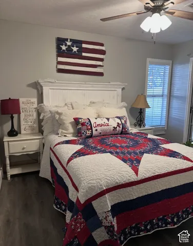 Room featuring wood-finish flooring, a white beadboard headboard with a crown molding cap, and a ceiling fan with multi-light fixture
