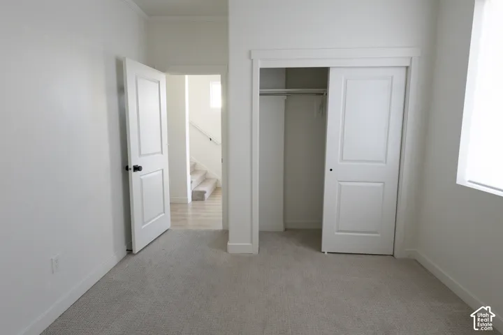 Interior room featuring wall-to-wall carpeting, a built-in sliding door closet, multi-panel doors with matte black hardware, and an oversized window