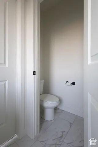 Restroom featuring large-format tile flooring with stone-pattern finish, dual-panel interior door, and matte black hardware